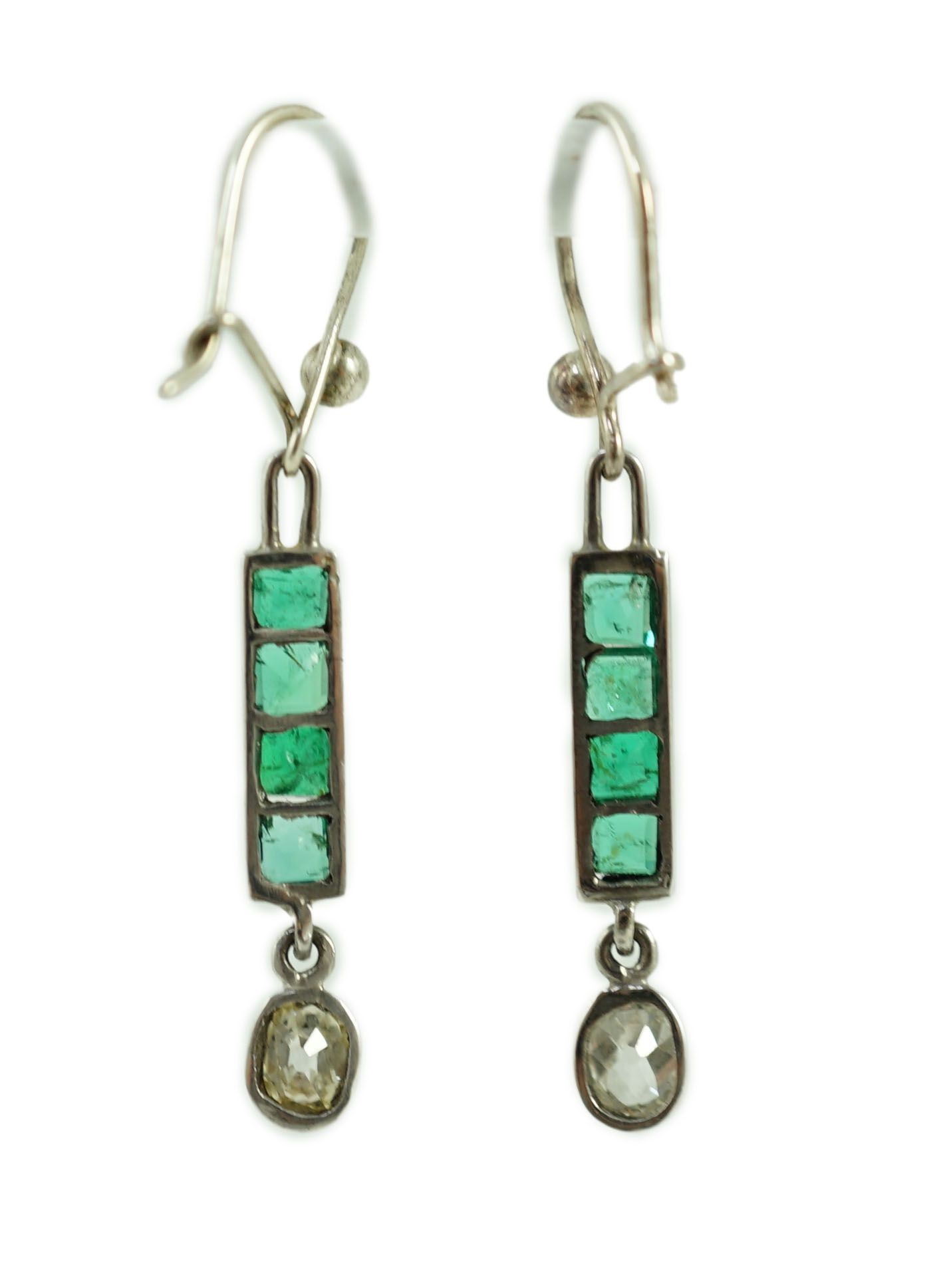 A pair of white gold, four stone emerald and single stone oval cut diamond set drop earrings